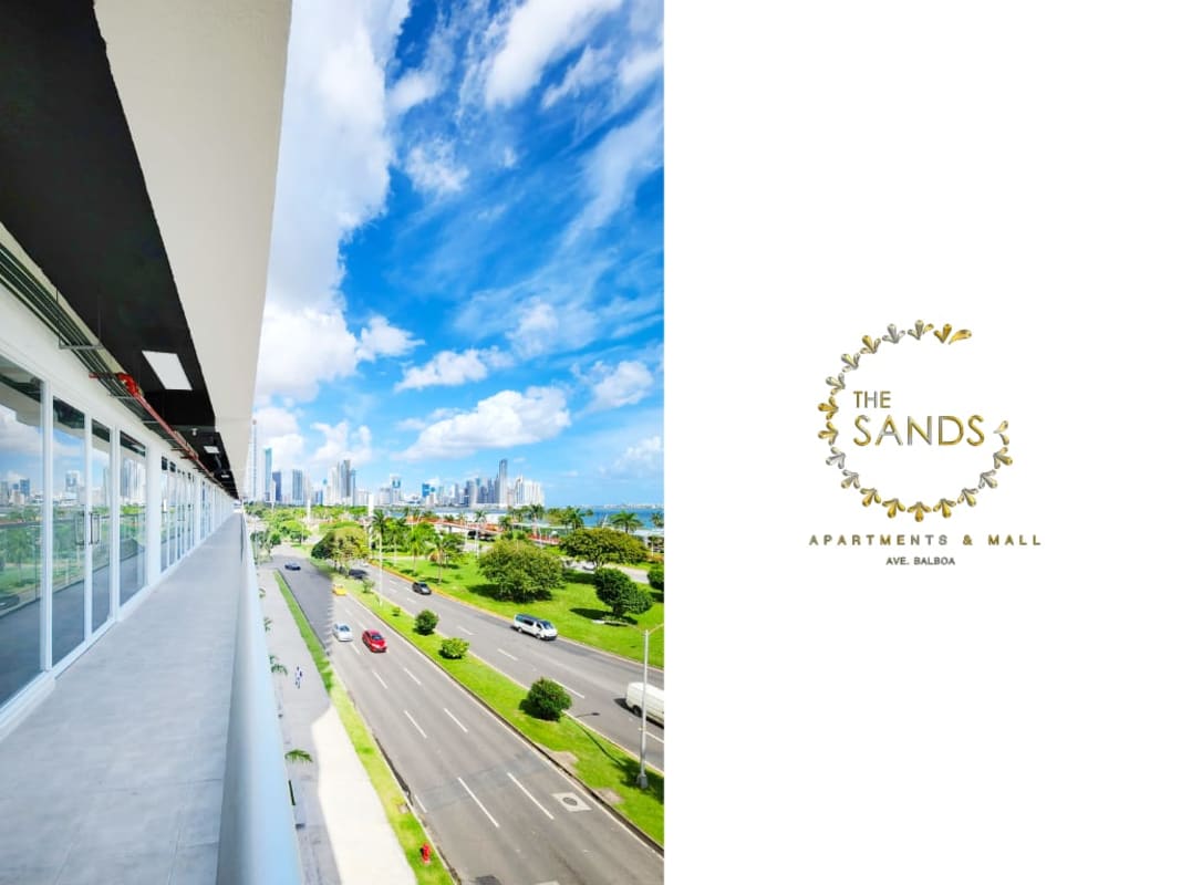 Balcony overlooks busy Avenida Balboa, waterfront park and Panama City skyline under blue sky