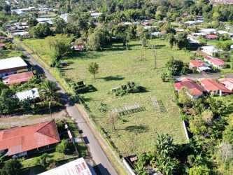 Aerial of large green land lot with homes and electric poles on paved streets Bugaba Panama