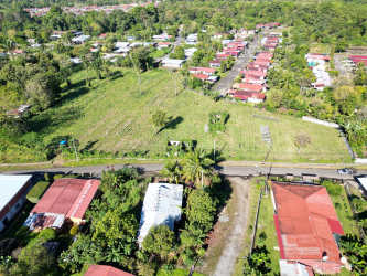Aerial showing green open land and nearby residential houses with red roofs in La Concepción Bugaba