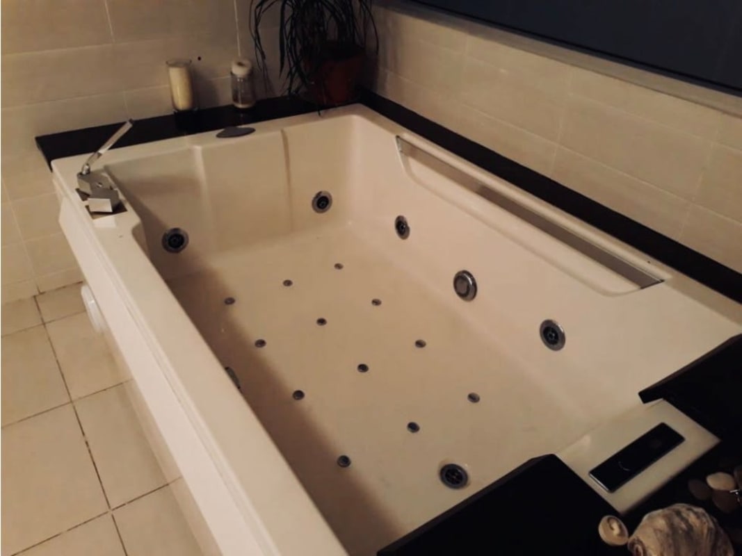 Bathroom with large jacuzzi tub, beige tiles and luxury fixtures in rental apartment Panama City