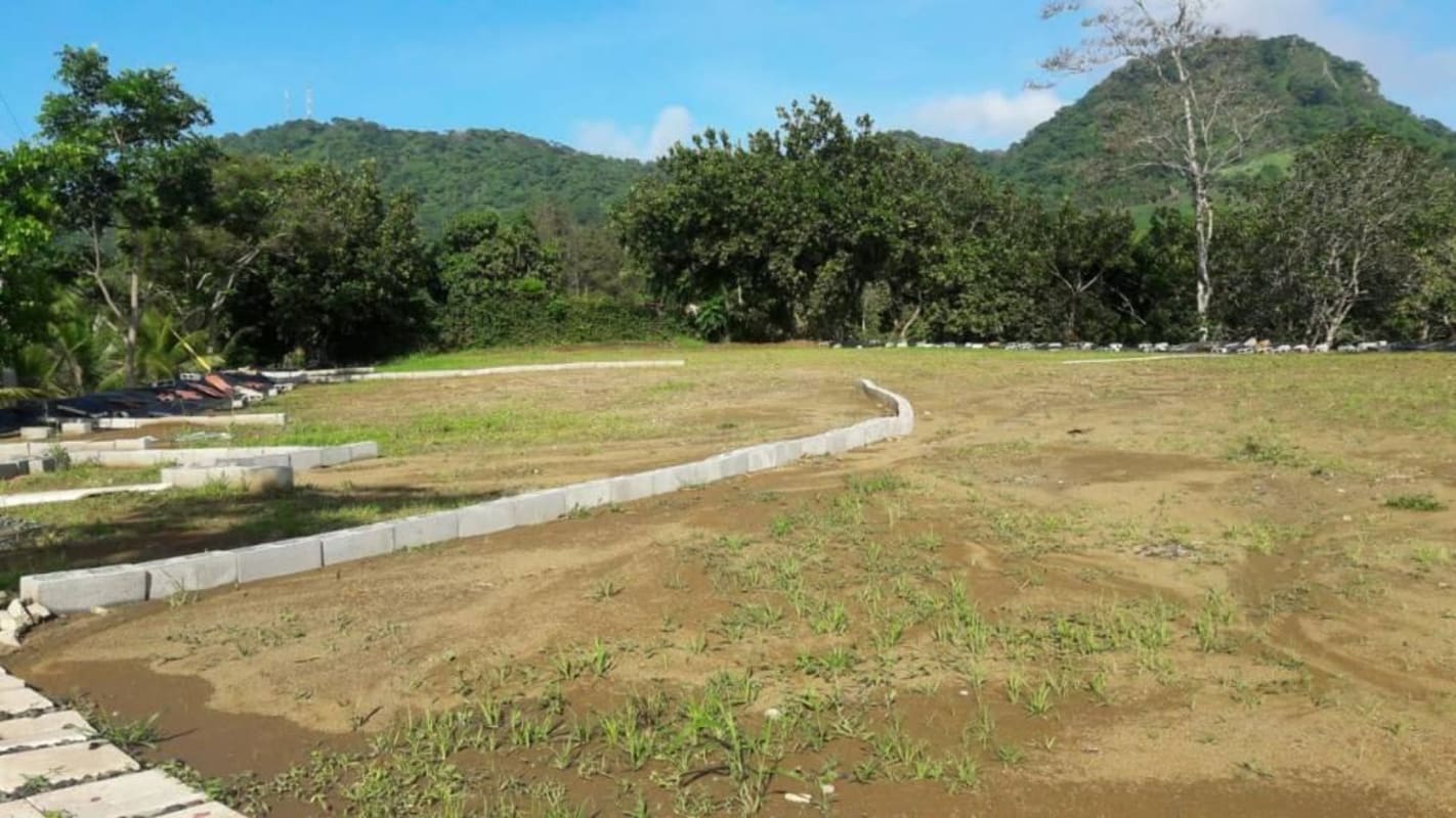 Wide semi-flat land with asphalt access road and tropical greenery in Las Cumbres Panama City