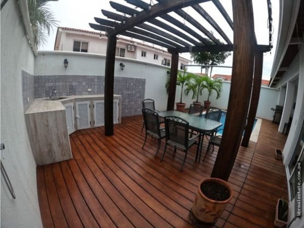 Covered patio with pergola, outdoor kitchen, dining set and pool in Costa Sur Panama