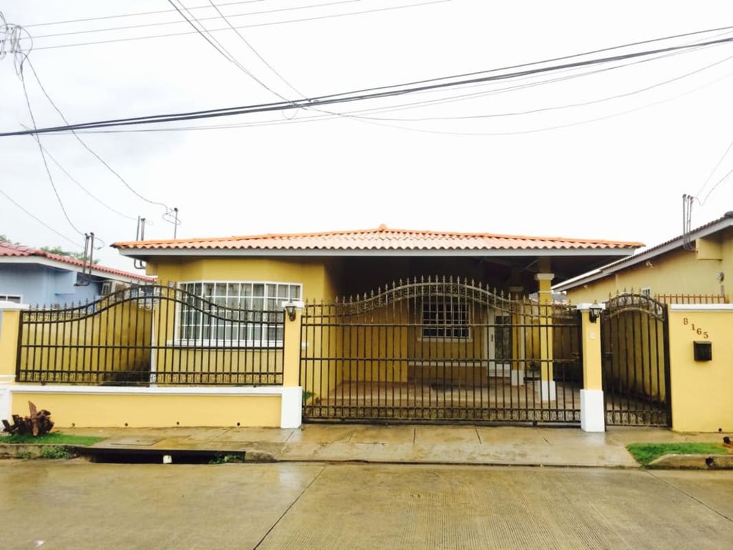 House frontal view with iron gate, covered parking, and terracotta roof Altos de Las Praderas Panama