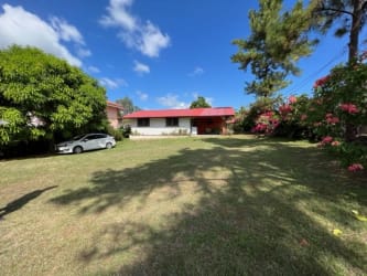 Single-story white house with red roof on large lawn in Coronado beach community Panama