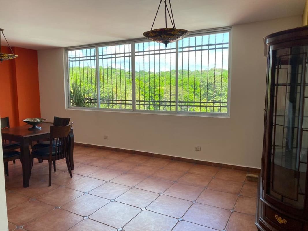 Large split-level living room with wrought iron staircase, tile floor, and panoramic windows Villa de las Fuentes Panama