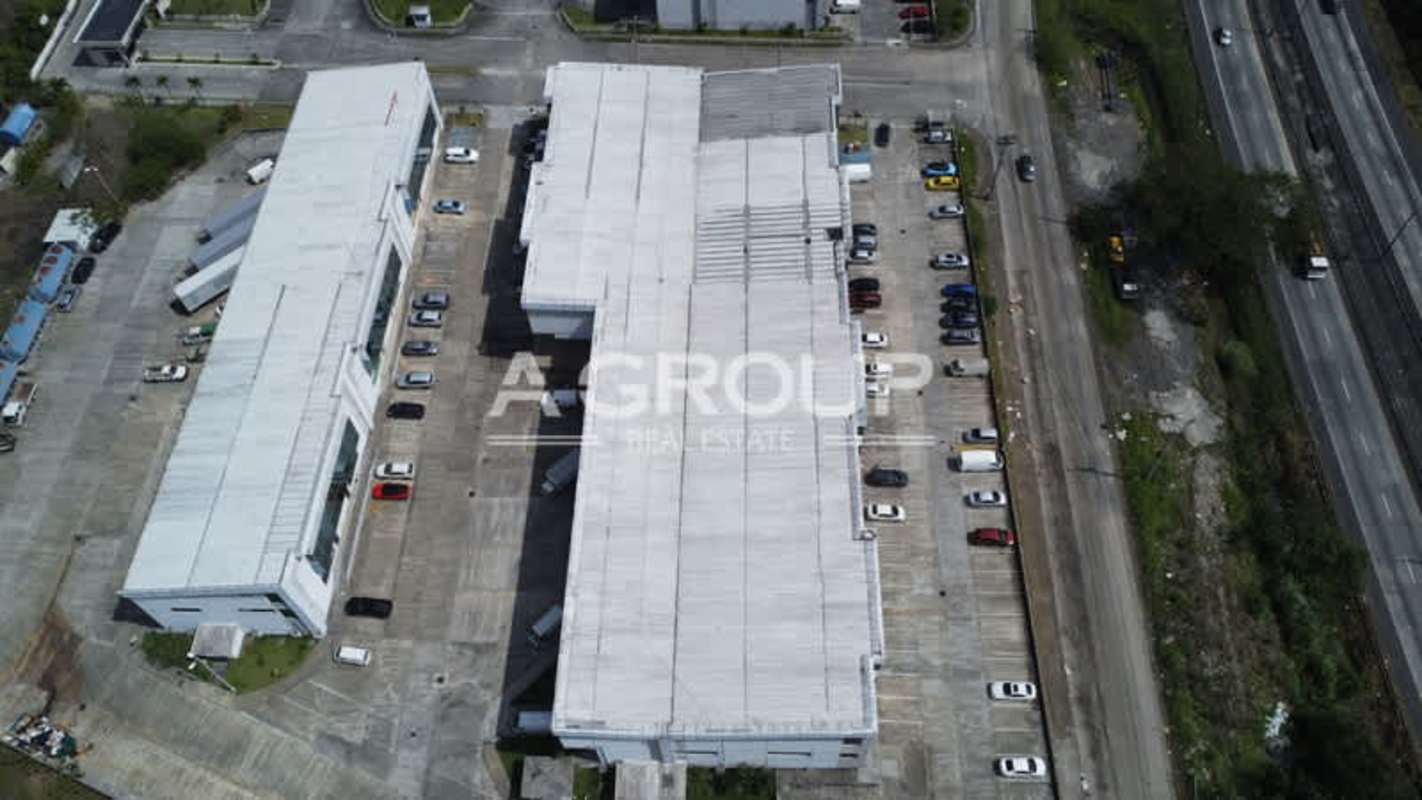 Aerial perspective of large multi-warehouse industrial complex with green surroundings at Parque Centenario Panama