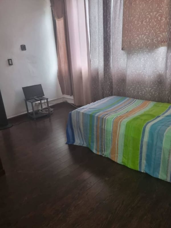 Bedroom with striped bedspread and city view window in Panama apartment