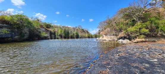 Calm river with rocky shore and greenery next to beach land Rio Mar San Carlos Panama