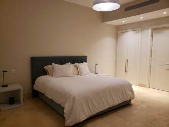 Spacious minimalist bedroom with soft colors and modern decor in Buenaventura luxury beach house Panama