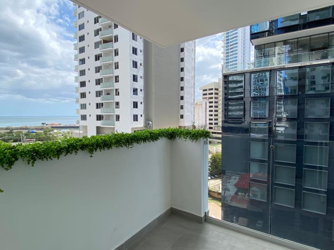Modern balcony with glass railing, decorative plants, ocean skyline vista Bella Vista Panama