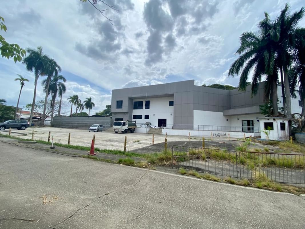 Modern commercial building exterior with large parking lot and palm trees in Albrook Panama