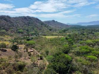 Main access dirt road bordered by trees with scenic hills Capira Panama