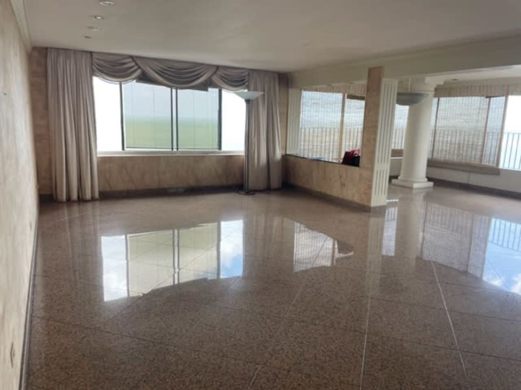 Large open living room with wood paneling and panoramic ocean skyline views in Coco del Mar penthouse Panama