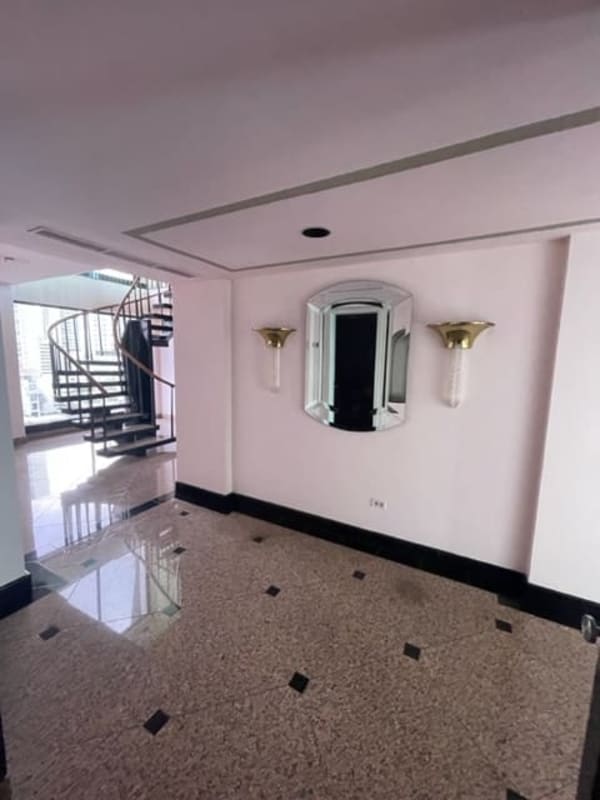 Spacious modern kitchen with white cabinetry, central island, and spiral staircase in luxury penthouse Coco del Mar Panama