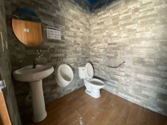 Public restroom with gray tiles, sink, urinal in commercial plaza Colón Panama