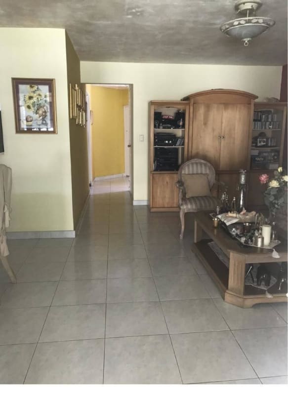 Traditional living room with tile floors, wooden furniture, and neutral wall colors in Green Valley residence Clayton Panama