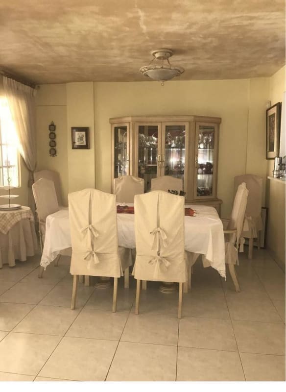 Large dining area with slip-covered chairs and china cabinet in Green Valley residence, Panama City