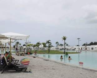 Large recreational lagoon pool with white sand beach area at Ibiza Beach Residences Panama