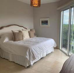 Bright bedroom with sliding doors opening onto balcony with nature views in Buenaventura Panama beach condo