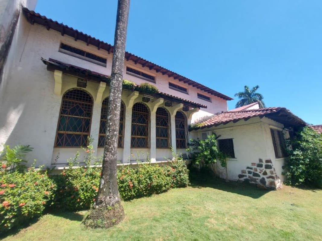 White stucco walls, tile roof, arches, garden palm tree on historic mixed-use building Panama City