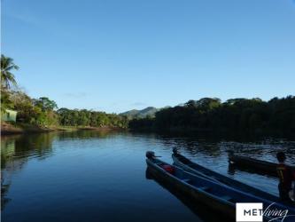 Serene river view from property edge with canoes and lush greenery in Nuevo Vigia Colon Panama