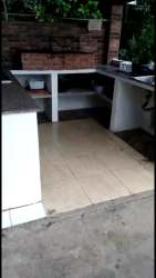 Rustic style outdoor kitchen with brick BBQ, concrete counters, garden view in Las Lajas Panama