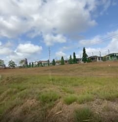 Open commercial land with sparse grass, distant buildings near La Chorrera Panama City area