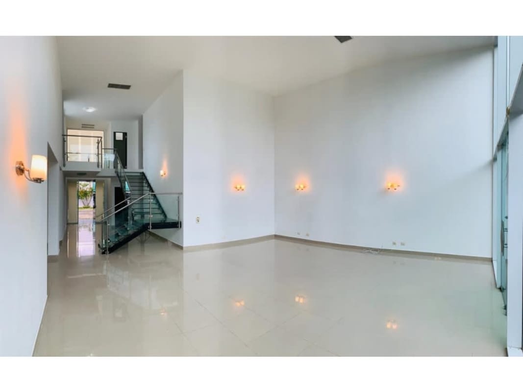 Bright modern living room with large windows, glass staircase, tile floors in PH Costa Esmeralda Costa Sur Panama City
