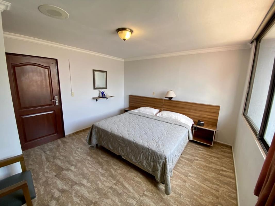 Minimalist guest bedroom double bed bright window in hotel Panama