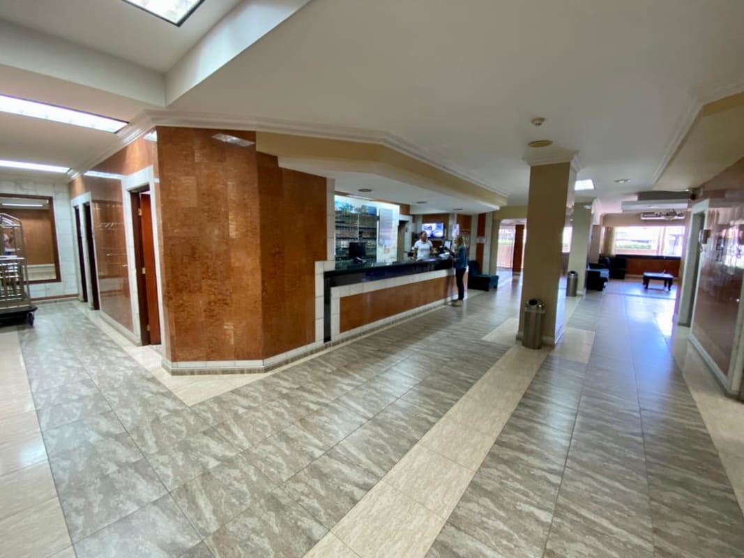 Large hotel reception lobby area with desk, seating and marble floor