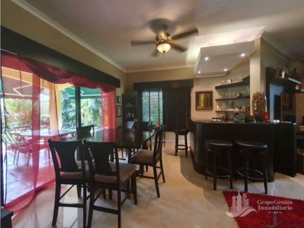 Spacious dining area with wooden furniture and chandelier overlooking garden