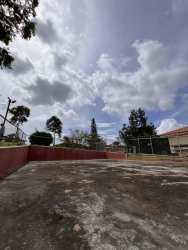 Large concrete yard with BBQ area, red fence, trees Chitré property