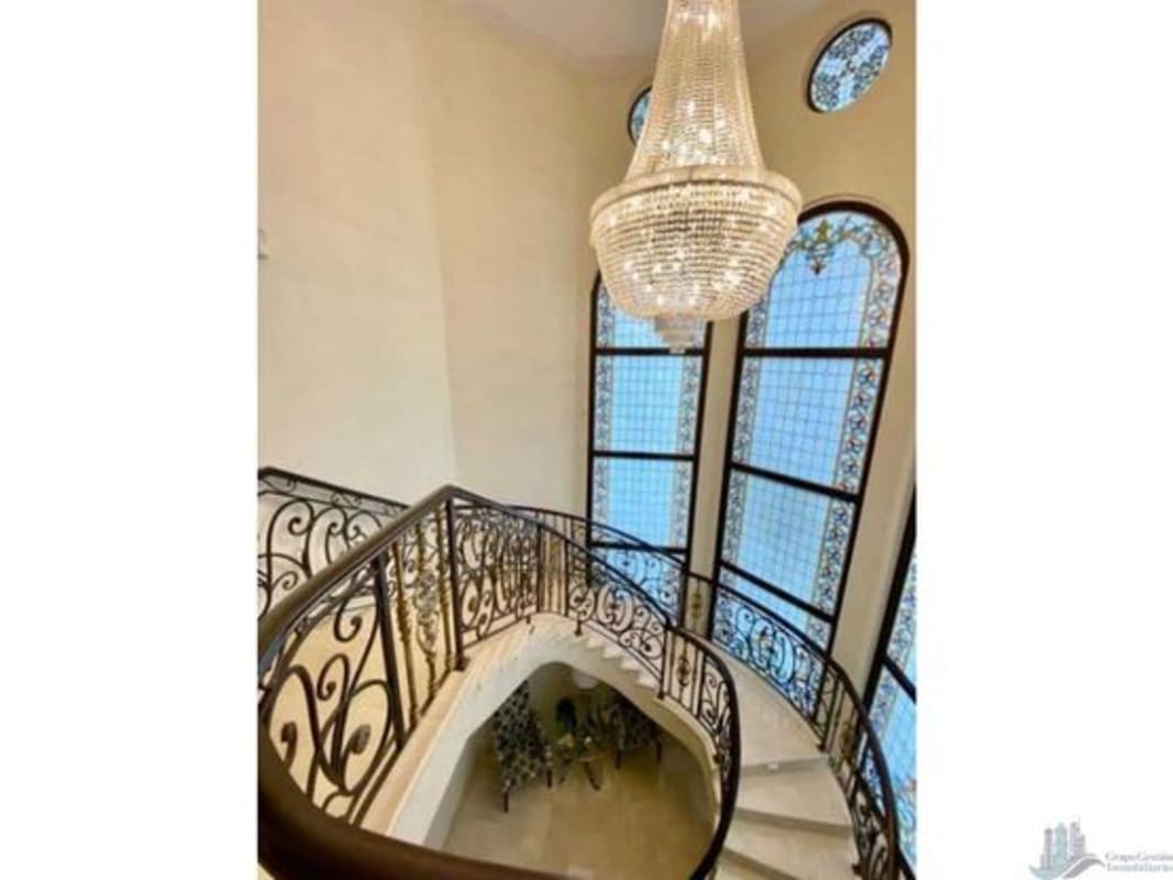 Luxury staircase with chandelier, wrought iron railings and stained glass windows in golf estate villa Panama