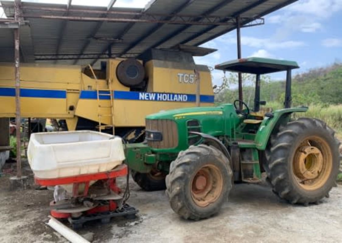 Shelter with green tractor and yellow harvester parked at rice farm Chepo Panama