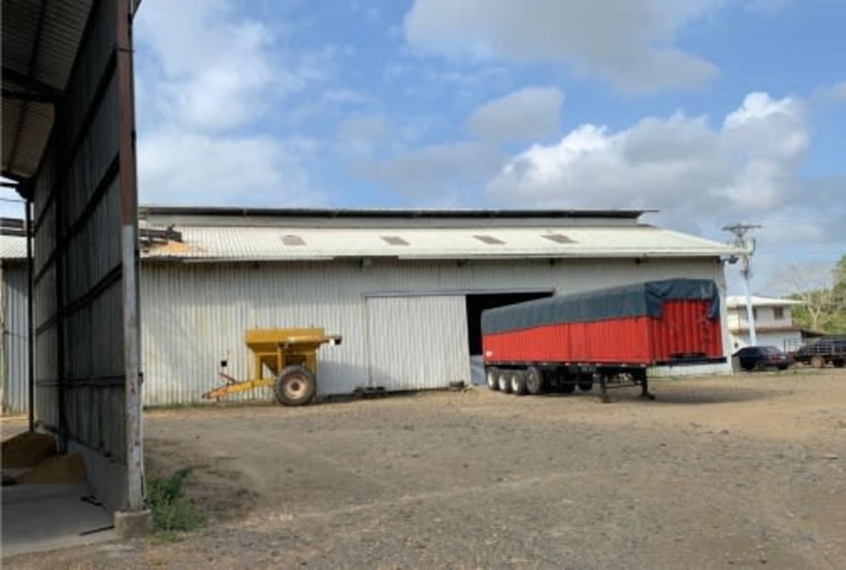 Exterior view of large metal warehouse building and parked red trailer Chepo Panama