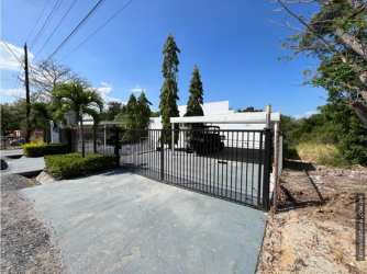 Secured driveway black gate tropical greenery beach home for sale