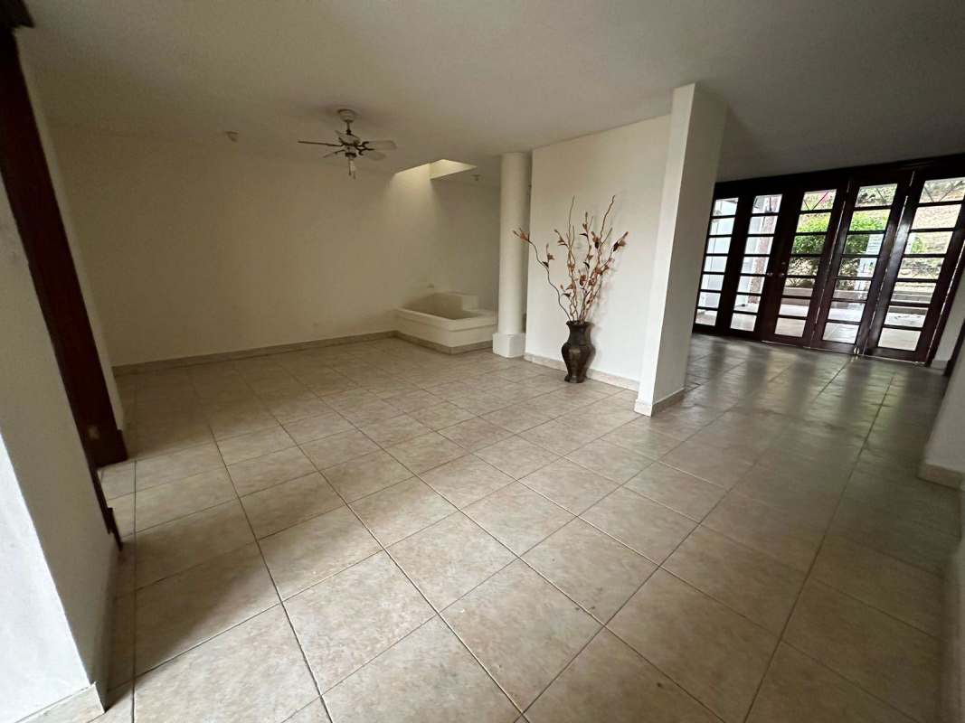 Spacious living room with tile floors, ceiling fan, French doors opening to terrace at Altos de La Loma house Panama