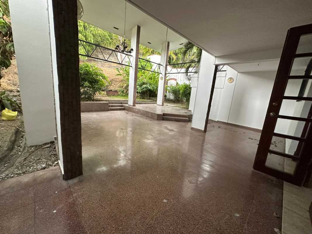 Covered outdoor patio area with terrace steps, surrounding plants and garden in Altos de La Loma house Panama