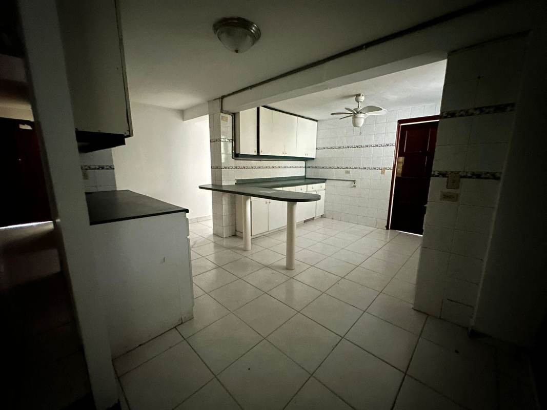 Traditional kitchen with black countertops, white cabinets, tile flooring, breakfast bar and ceiling fan in Altos de La Loma