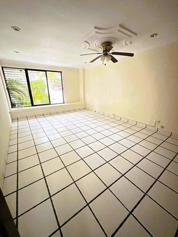 Bedroom with light tile floors, ceiling fan, security window bars in Altos de La Loma house Panama