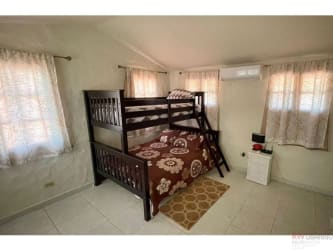 Open concept living dining kitchen with high ceiling exposed beams tile floor Playa Malibú house Panama