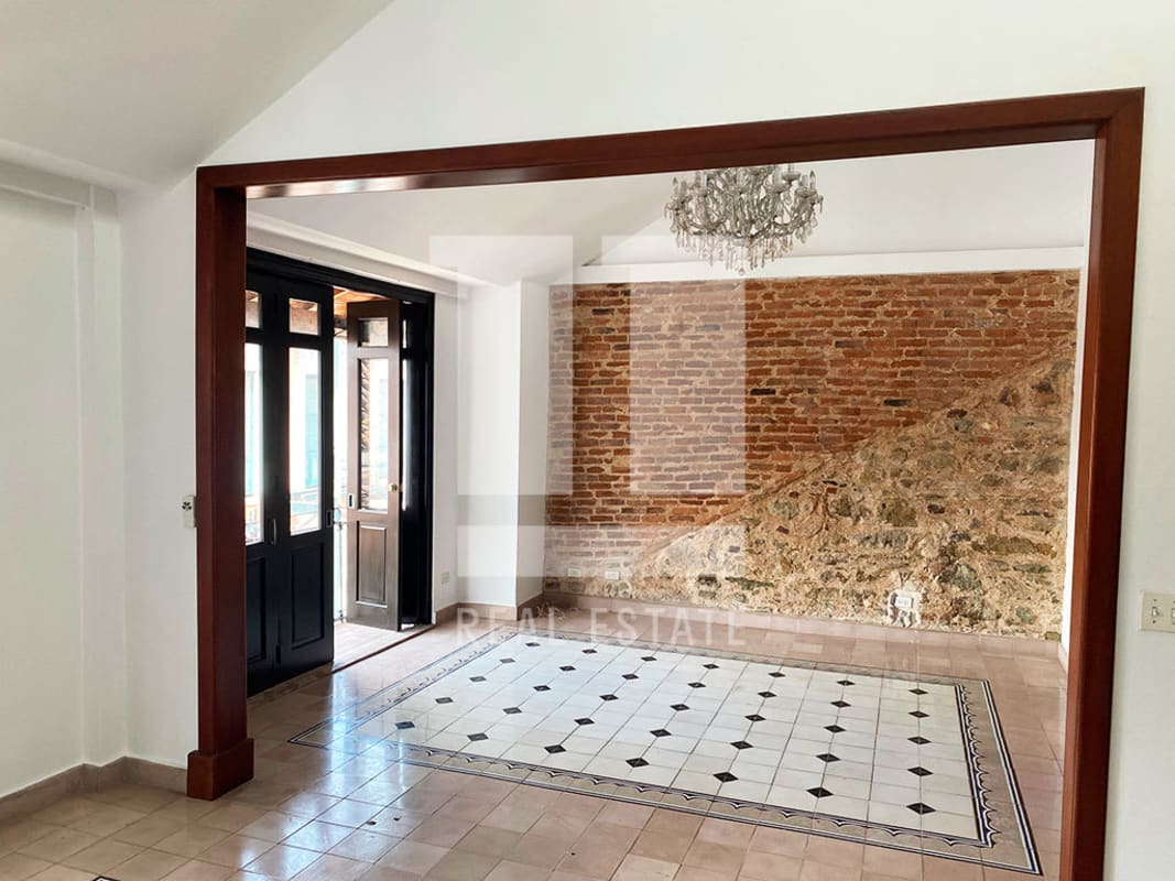 Rustic living room with exposed calicanto stone and chandelier in Casco Viejo apartment Panama