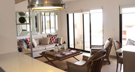 Bright coastal living room with wicker chairs and large sliding glass doors Playa Malibu Panama