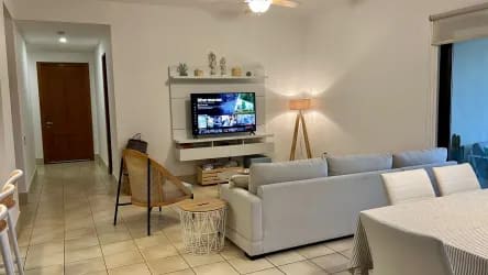 Modern minimalist living area with sectional sofa and TV in luxury Buenaventura condo Panama