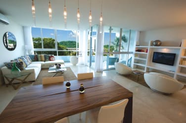 Open-plan living and dining room with floor-to-ceiling acoustic windows in Casa Bonita Panama Pacifico.