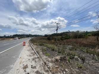 Open commercial land parcel facing busy highway with utilities Panama West region