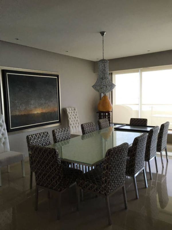Modern dining area with glass table, upholstered chairs and natural light in Costa del Este condo