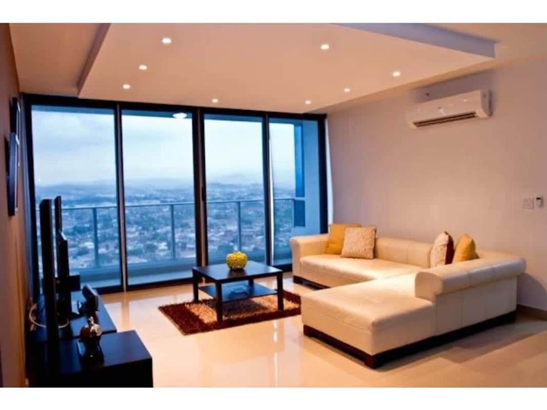 Living area with sectional sofa and floor-to-ceiling windows offering city views in PH Top Towers Costa del Este Panama City