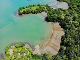 Aerial of secluded peninsula on lush Isla Brava with tropical trees and ocean coastline