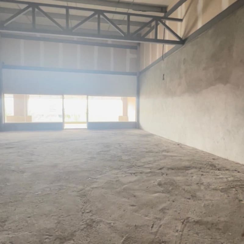 Warehouse style unfinished space with concrete floor and large storefront window in Paseo Albrook Mall Panama City